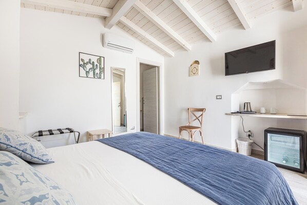 A bedroom with a bed, a television, a small refrigerator, and a chair. - Clara Domus - Matrimoniale (Gallipoli)