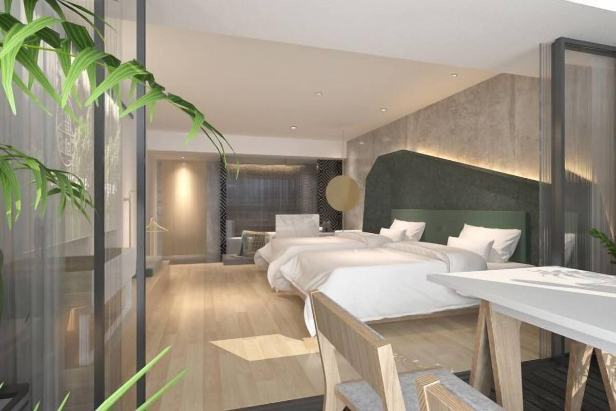 Ein modernes Hotelzimmer mit einem großen Bett, einem Schreibtisch und Blick durch eine Glaswand.