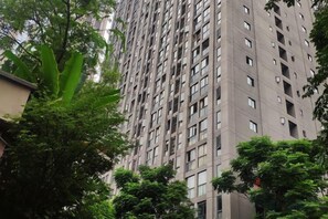 Een hoog appartementencomplex met meerdere balkons, omringd door bomen.