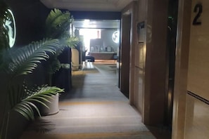 Een hal met een kamerplant, een receptiebalie en een bord met daarop kamer 2.