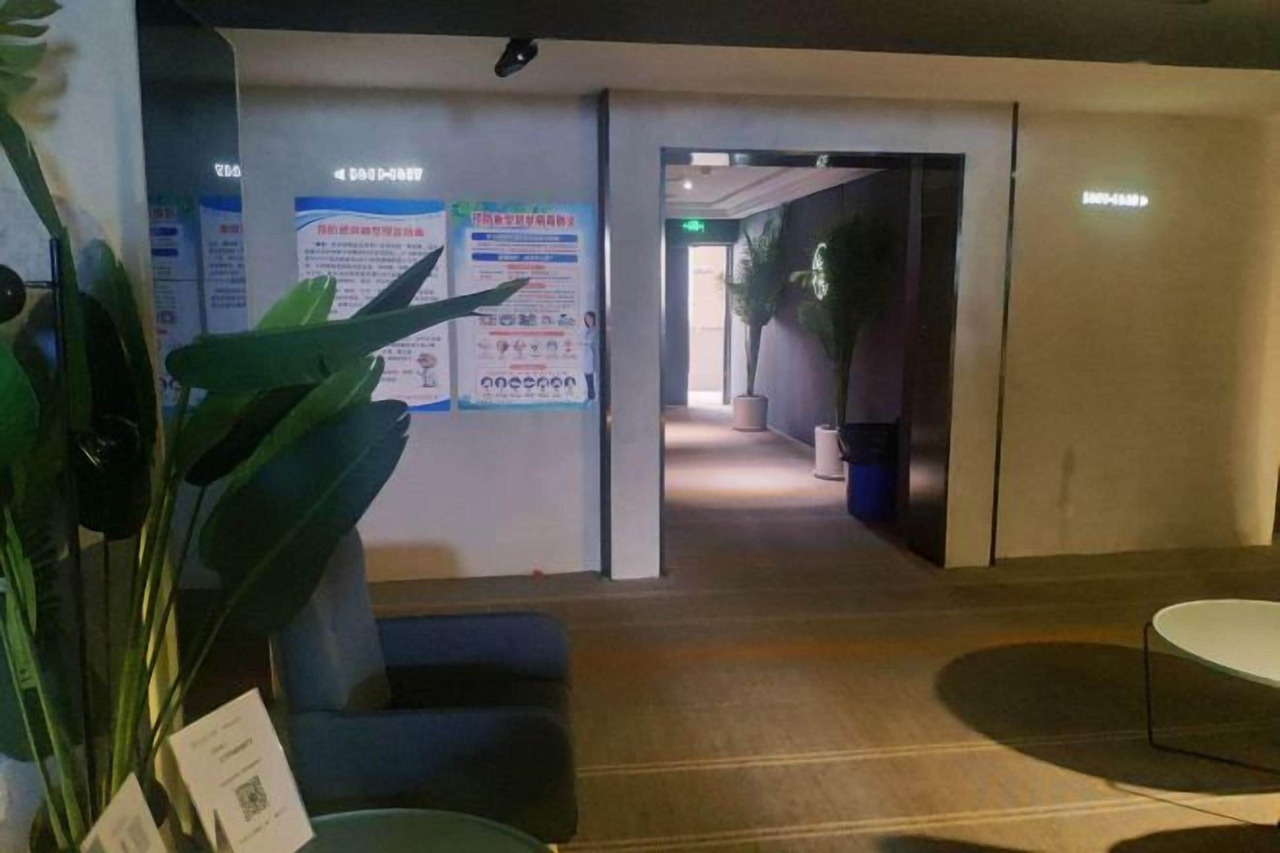A hotel lobby with a reception desk, seating area, and a corridor leading to other rooms.