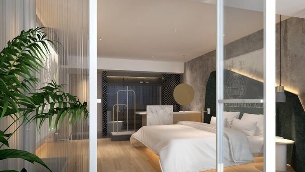 Ein modernes Schlafzimmer mit einem großen Bett, einem Schreibtisch und einem Stuhl. Eine Pflanze steht links.