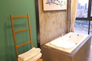 Une salle de bain avec une grande baignoire, une échelle en bois et une pile de serviettes.
