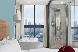 Une chambre d’hôtel moderne dotée d’une grande fenêtre, d’une baignoire et d’une douche.