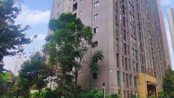 A high-rise building with multiple floors, surrounded by greenery and trees.