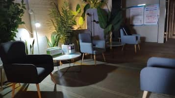 A seating area with modern chairs and a table, surrounded by potted plants and a lamp.