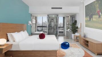 A modern hotel room with a large bed, a television, and a view of the city.