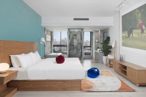 Ein modernes Hotelzimmer mit einem großen Bett, einem Fernseher und Blick auf die Stadt.
