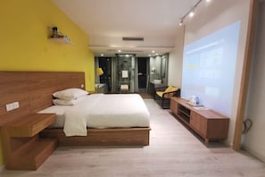 Een moderne hotelkamer met een bed, een bureau en een groot scherm waarop een presentatie wordt weergegeven.