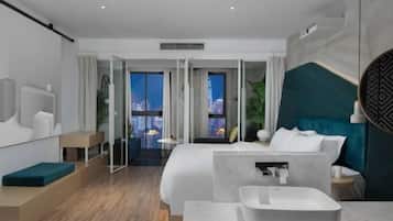 Una habitación de hotel moderna con cama, baño, vistas a la ciudad y un balcón.