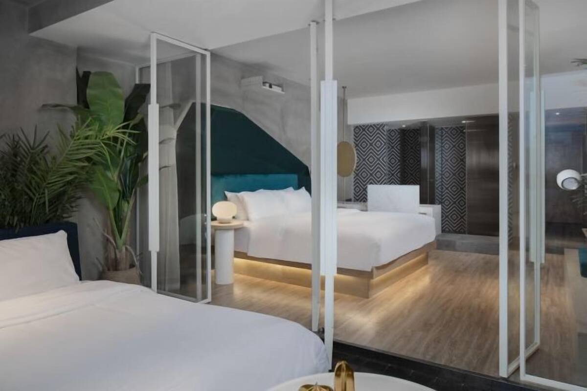 Ein modernes Hotelzimmer mit Bett, Nachttisch, Spiegel und Duschbereich.