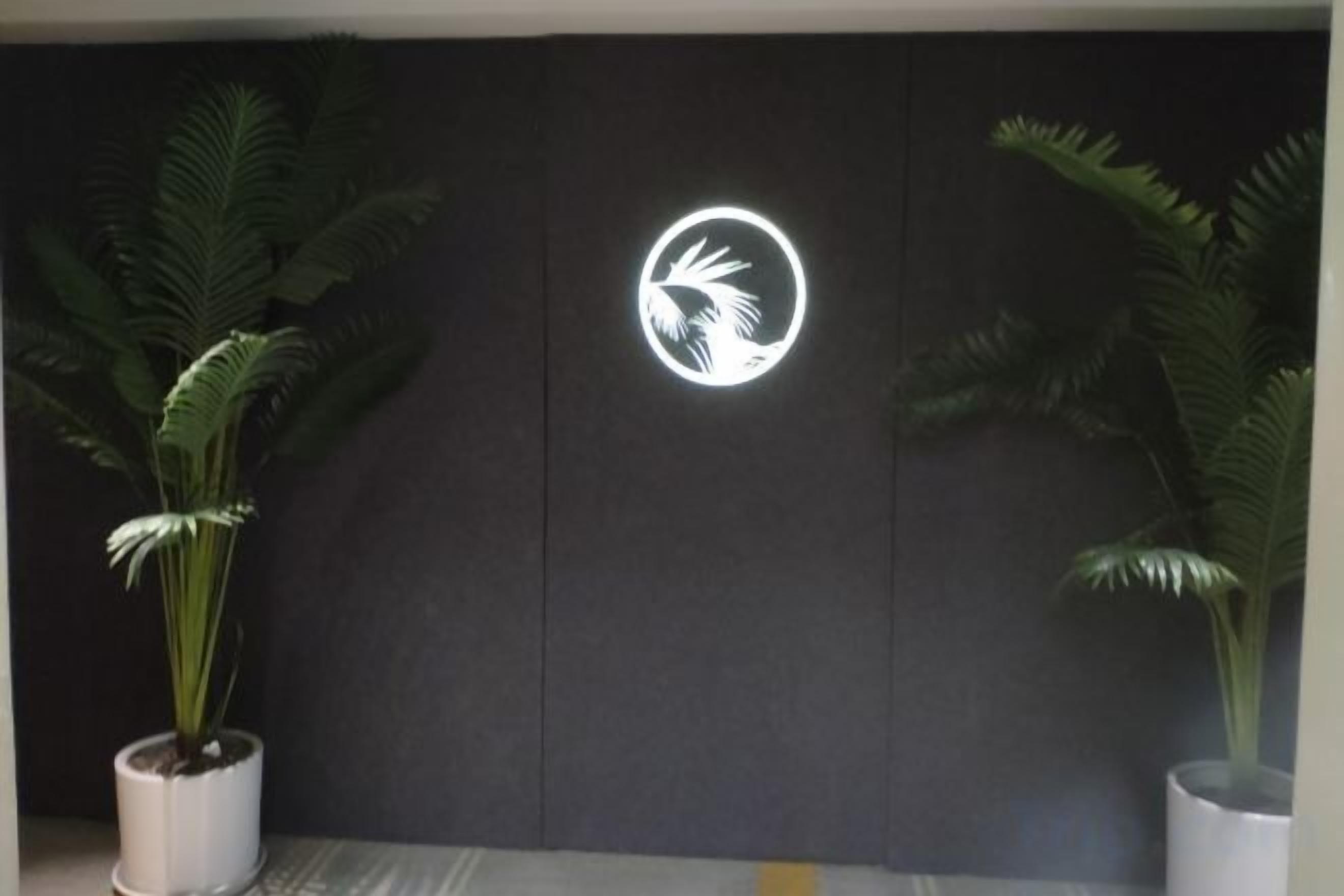 A wall with a logo and two potted plants.