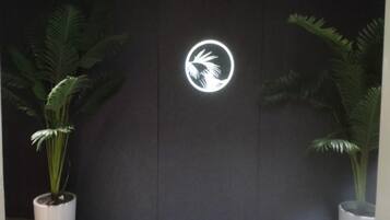 A wall with a logo and two potted plants.