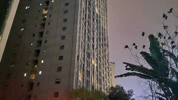 A tall building with multiple floors and windows, surrounded by trees and foliage.