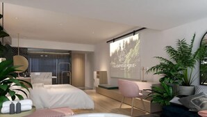 Ein modernes Hotelzimmer mit einem großen Bett, einem Schreibtisch, einem Sessel, einer Badewanne und einer Projektionsleinwand, auf der 'LA CARTOUCHERIE' zu sehen ist.