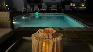 En pool med solstolar och ett bord av rotting med ett ljus.