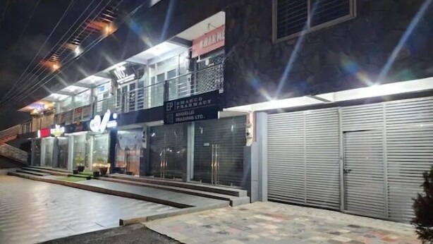 A building with multiple storefronts, including a pharmacy and a bank. - Masterpiece 1 bedroom  (Accra)