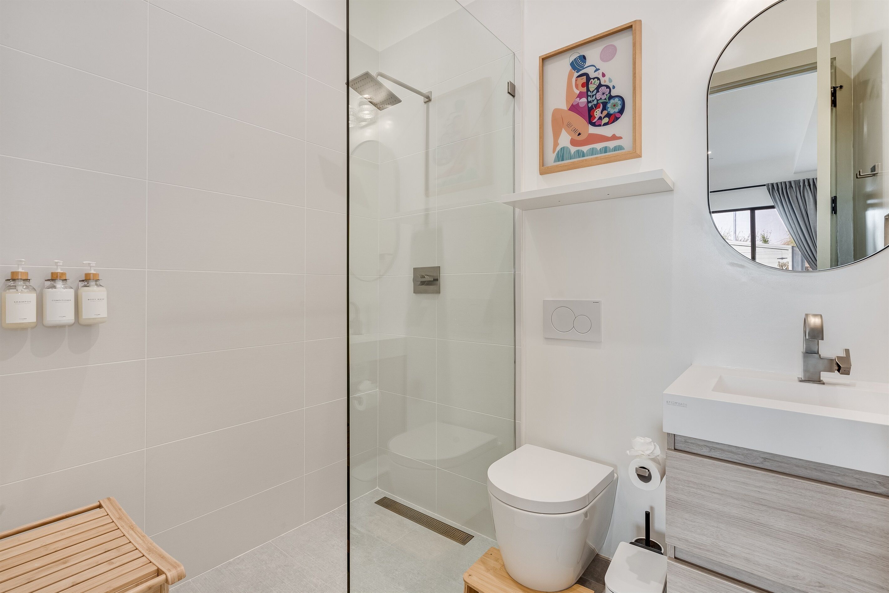 Une salle de bain moderne avec une douche à parois de verre, des toilettes, un lavabo avec un miroir et un banc en bois.