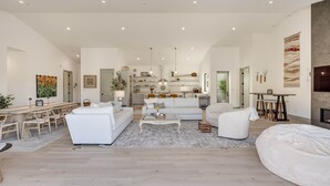 Ein geräumiges Wohnzimmer mit einem großen weißen Sofa, einem Couchtisch und einem Essbereich mit Holzkästen.