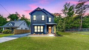 A two-story house with a dark blue exterior, a front porch, and a well-maintained lawn. - 19th Hole - Pickelball, Park, Walk to Downtown (Southern Pines)