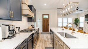 A modern kitchen with dark cabinets, a white countertop, and a built-in stove. - 19th Hole - Pickelball, Park, Walk to Downtown (Southern Pines)