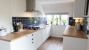 A modern kitchen with white cabinets, a wooden countertop, and a blue-tiled backsplash. - The Barn, Chipping Norton (Chipping Norton)