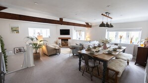 A spacious living area with a fireplace, a dining table set for four, and a cozy seating arrangement. - The Barn, Chipping Norton (Chipping Norton)