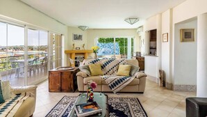 A spacious living room with a large window, a sofa, a coffee table, and a view of the outdoors.