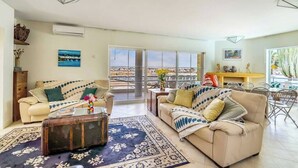 A spacious living room with a sofa, coffee table, and a view of the city through large windows.