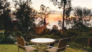 A round table with four chairs in a garden setting with a sunset view.