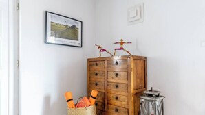 A wooden dresser with multiple drawers, a wicker basket with folded items, and a metal lantern on the floor. - Villa Oceano by Indigo (Carvoeiro)