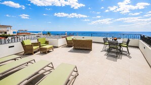 A terrace with outdoor seating, a table, and a view of the sea. - Villa Oceano by Indigo (Carvoeiro)