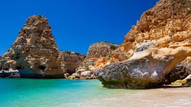 A coastal scene with clear turquoise water, rocky formations, and a sandy beach. - Villa Oceano by Indigo (Carvoeiro)
