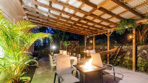 An outdoor patio area with a pergola, seating, a fire feature, and potted plants. - KONA CLOUD FOREST GUEST HOUSE~3 Bedrooms~ (Kailua-Kona)