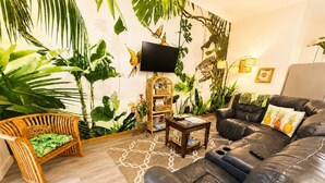 A living room with a sofa, a wooden chair, a small table, and a TV mounted on the wall. - KONA CLOUD FOREST GUEST HOUSE~3 Bedrooms~ (Kailua-Kona)