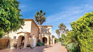 A building with a tiled roof, arched doorways, and a paved pathway. - Villa Concha by Indigo (Carvoeiro)