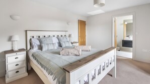 A bedroom with a bed, bedside tables, a nightstand, a wooden bench, a mirror, and a door leading to another room. - Cherry House - sleeps 8 guests  in 4 bedrooms (Thornham)