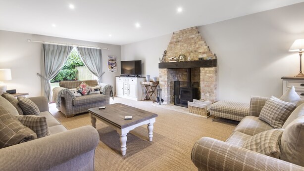 A living room with a fireplace, sofas, and a television. - Cherry House - sleeps 8 guests  in 4 bedrooms (Thornham)