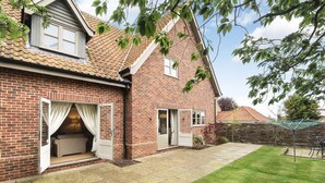 A brick house with a tiled roof, a covered patio, and a lawn. - Cherry House - sleeps 8 guests  in 4 bedrooms (Thornham)