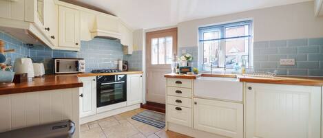 A kitchen with white cabinets, a microwave, an oven, and a window with a view.