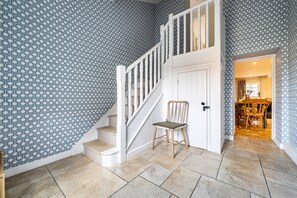 A staircase with a white railing leading to a door, a wooden chair, and a patterned wall. - Cherryhill - sleeps 5 guests  in 3 bedrooms (North Creake)