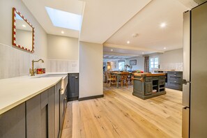 A modern kitchen with a skylight, wooden flooring, and a dining area with a table and chairs. - Cherryhill - sleeps 5 guests  in 3 bedrooms (North Creake)