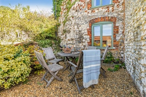 An outdoor seating area with a stone wall, wooden furniture, and a table with a basket.