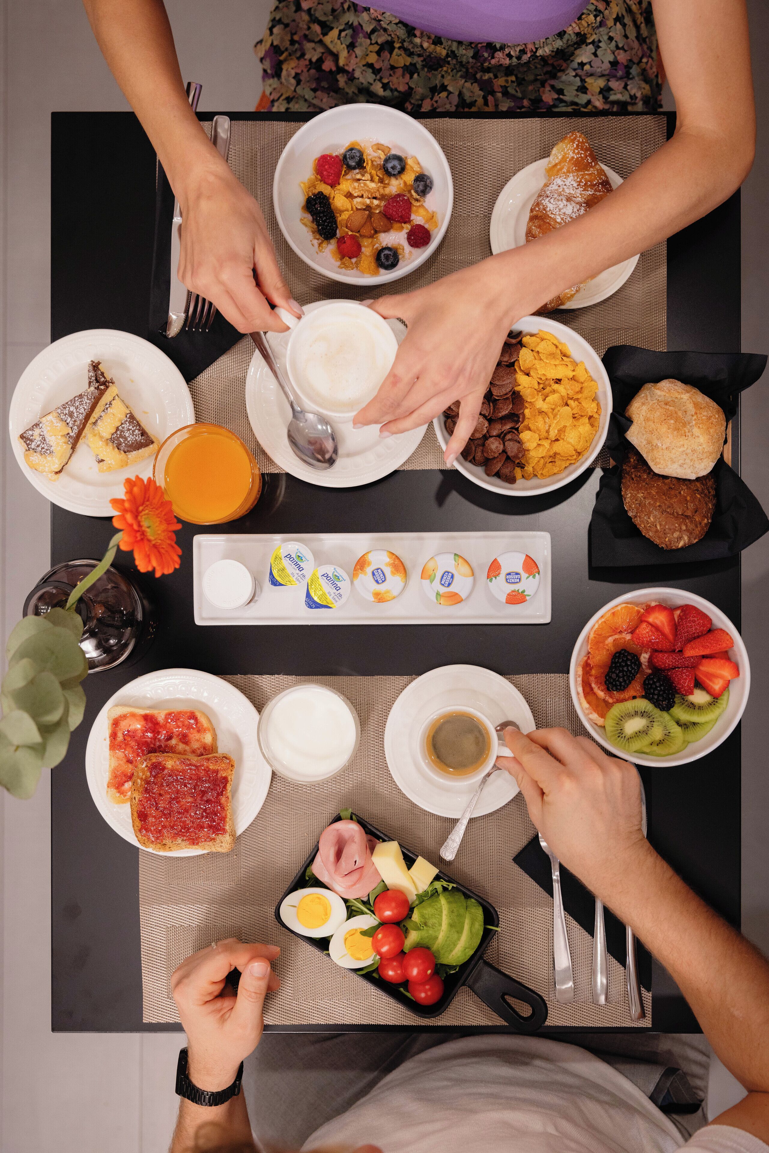Una mesa de desayuno con diferentes platos, como cereal, tostadas, fruta y huevos.