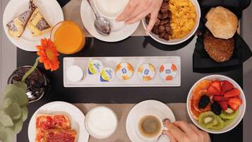 Una mesa de desayuno con diferentes platos, como cereal, tostadas, fruta y huevos.