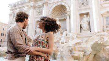 A couple standing in front of a grand architectural structure with intricate carvings and sculptures.