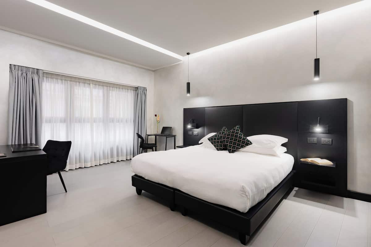 Una habitación de hotel moderna con una cama grande, un escritorio y una silla.