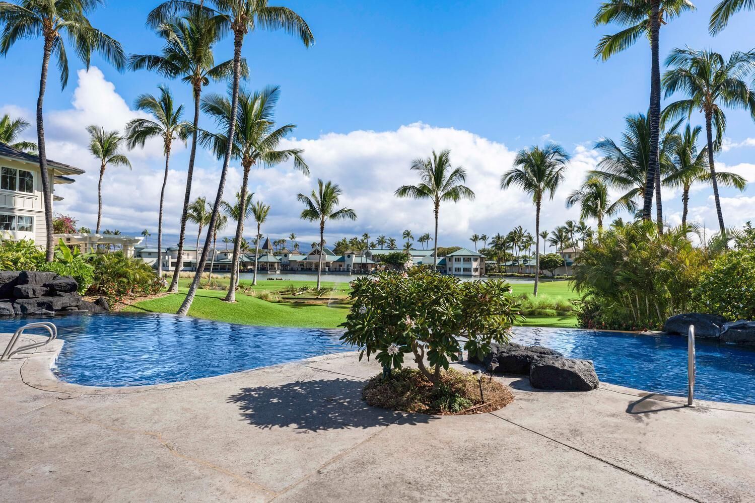 A resort with a swimming pool, palm trees, and a golf course.