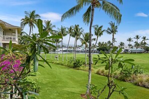 A well-maintained golf course with palm trees, a pool, and a building with a white facade.