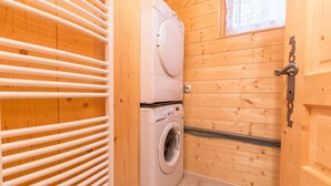 Ett litet och praktiskt tvättrum med tvättmaskin och torktumlare, träväggar och ett fönster.